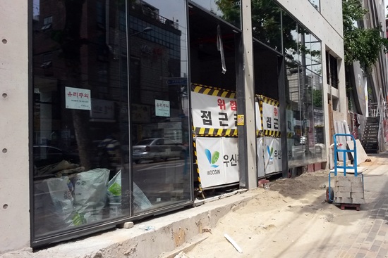 365일 학생 및 관광객들로 북적이는 서울 홍익대 앞 도로변입니다. 우후죽순 생겨나는 상점들로 이 일대 공사는 하루도 그칠 날이 없습니다. 그런데 이곳 도로, 부적절한 ‘수줍음’이 엿보입니다. 누구나 미리 알고 주의해야 할 ‘위험 접근금지’ 표지가 건물 내에 잠잠히 숨어 있습니다. 통행량이 많은 도로이기에 이 같이 위험 표지를 한 쪽에 치운 것이라고는 하지만, 원활한 통행보다 더 중요한 것은 ‘안전’이 아닐까요. 곁들여서, 다양한 국적의 사람들이 오가는 지역 특성상 ‘위험 접근금지’ 문구 아래 영문의 경고글인 ‘Watch Out’도 함께 적혀야 하지 않을까 합니다. 
<취재부>