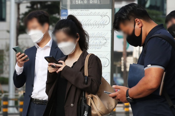 서울 시내 한 버스정류장에서 시민들이 스마트폰을 하고 있다. (사진제공: 뉴시스)