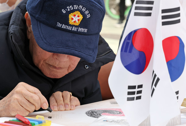 29일 오후 서울 은평구 명예도로 '권애라로'에서 열린 진관사 태극기 그리기 행사에서 6·25 참전유공자 어르신이 태극기를 그리고 있다. 사진제공 : 뉴시스
